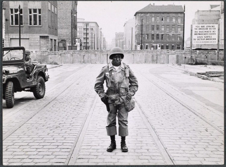 In defense of Western Civilization, an American soldier's hand rests on his gun in front of the Berlin Wall, Germany