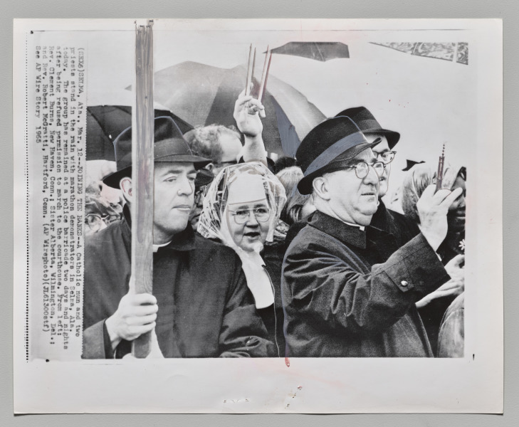 Joining the Ranks: A Catholic nun and two priests stand in the rain with marathon demonstrators in Selma, Alabama. The group has remained at a police barricade two days and nights after being refused permission to march to the courthouse. From left: Reverend Clement Burns, New Haven, Connecticut; Sister Alberta, Wilmington, Delaware; and Reverend Robert McGratti, Hartford, Connecticut, March 12, 1965