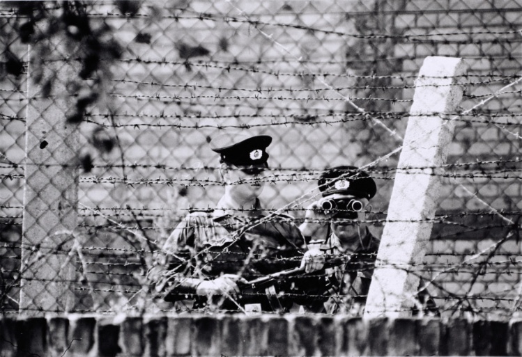 Berlin Wall patrol guards looking through binoculars and barbed wire