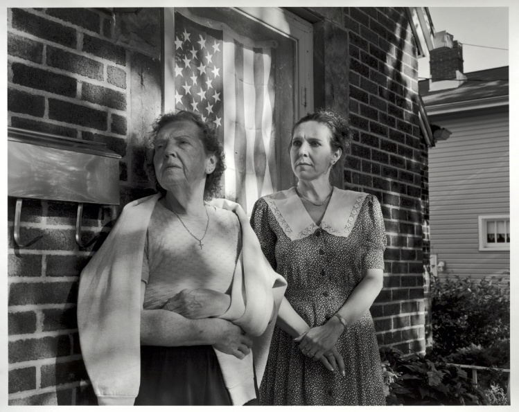 Marjorie Angel with daughter, Rebecca Barile, on Rebecca's porch with flag, Akron, Ohio
