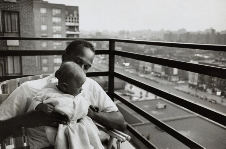 Sociology student with his 3 month old daughter on the balcony of his apartment, Harlem, New York City, USA