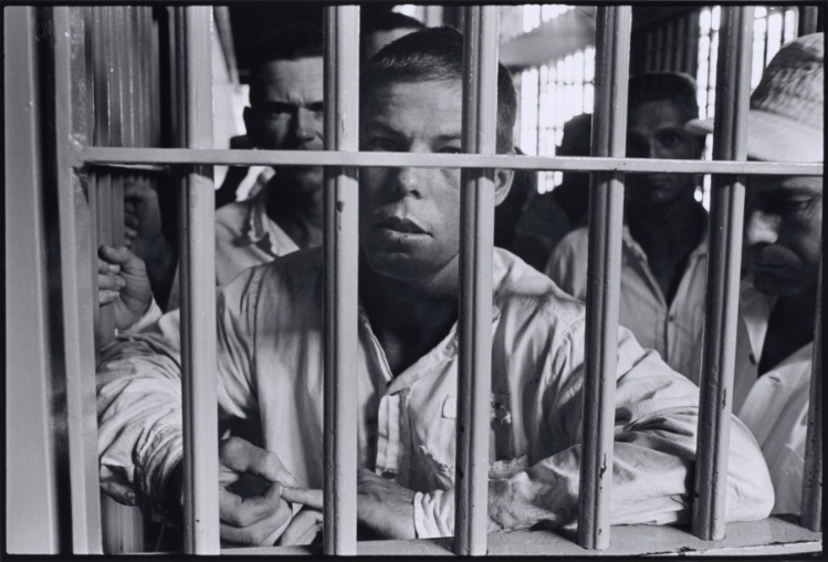 Cell Block (face behind bars, other prisoners behind him)