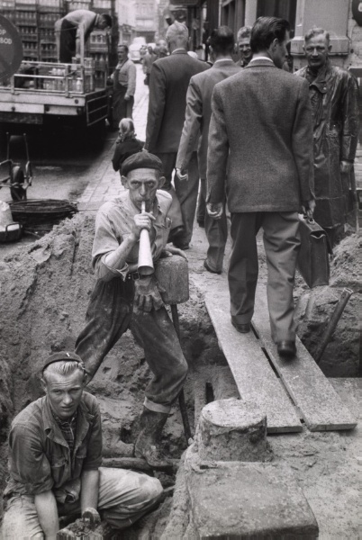 Worker blows horn, as telephone lines are fixed underground, Amsterdam, Holland