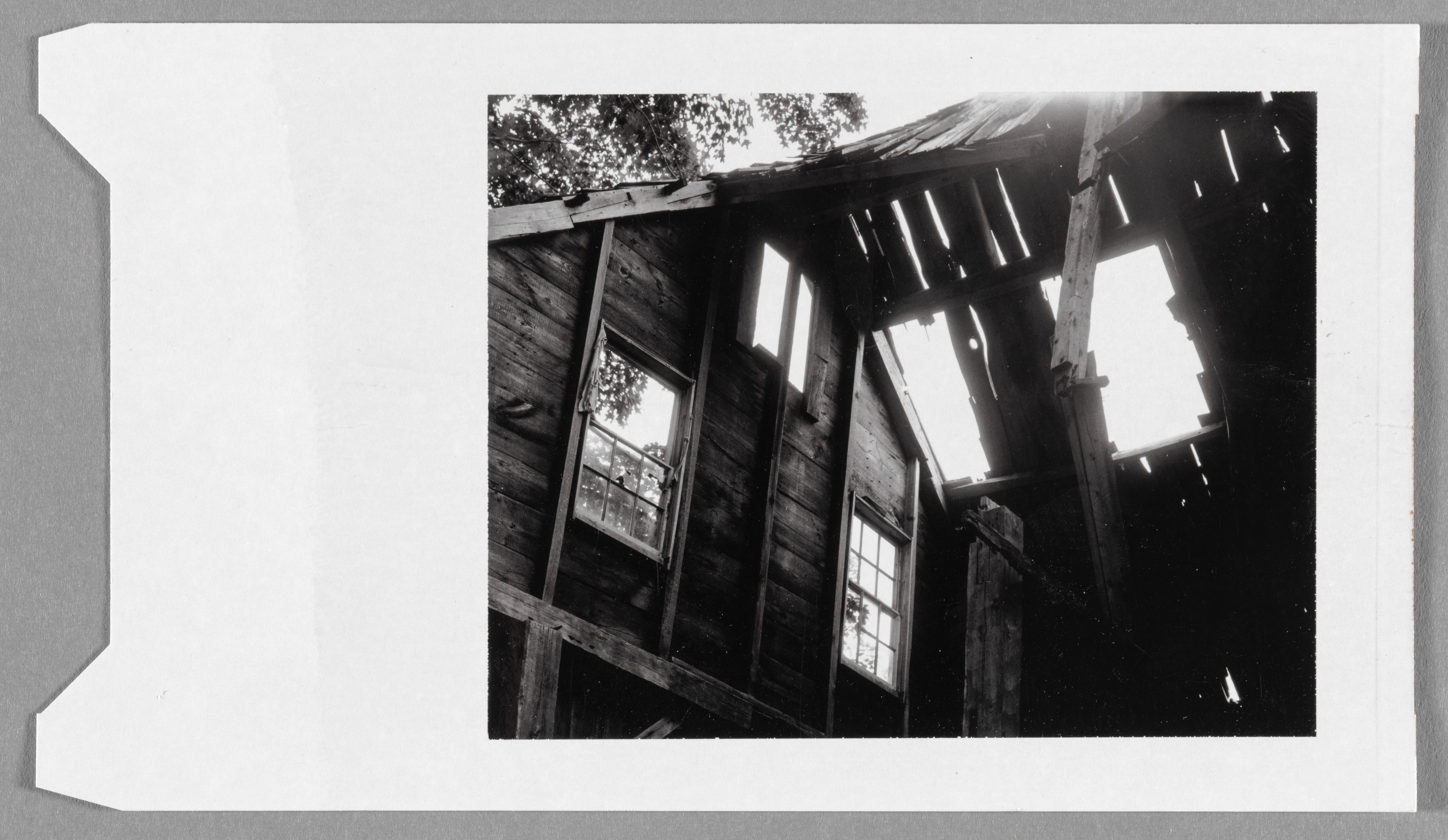 Untitled (run-down house interior with light streaming through holes in roof)