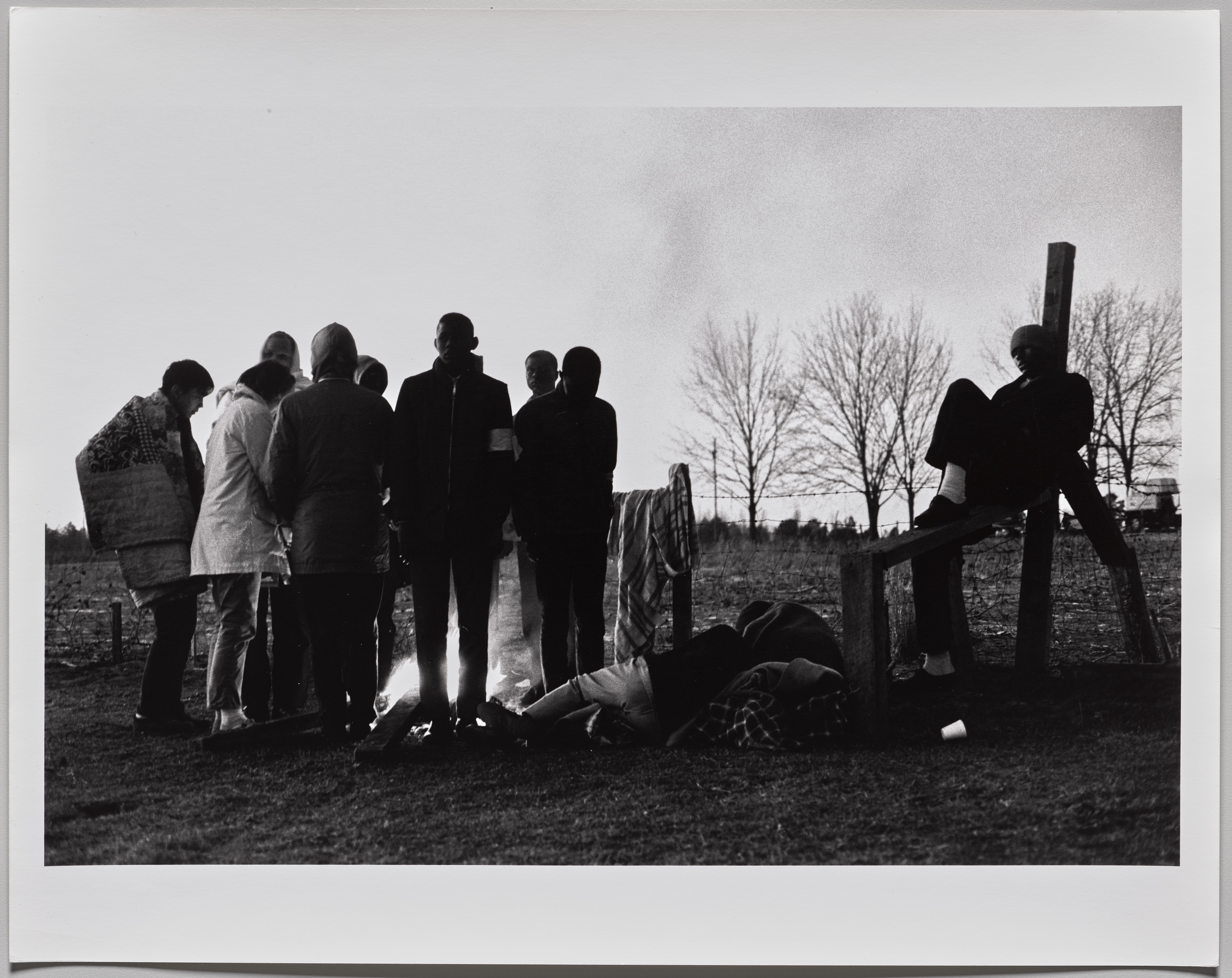 Hardcore marchers huddle by an early morning fire. Some three hundred went the entire distance camping by the road. Other marchers returned to their homes at night or slept in motels. March 1965