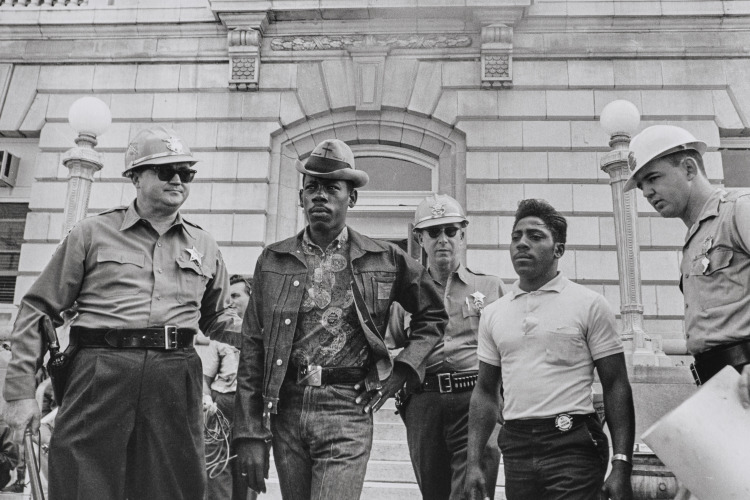 Sheriff Jim Clark arrests two demonstrators who displayed placards on the steps of the federal building in Selma, Alabama