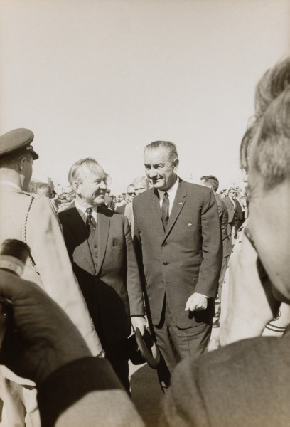 LBJ walking into a crowd of military men and reporters