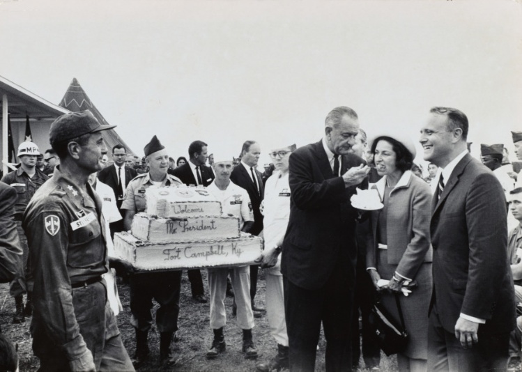 LBJ feeding Lady Bird a piece of cake from troops at Fort Campbell, Kentucky