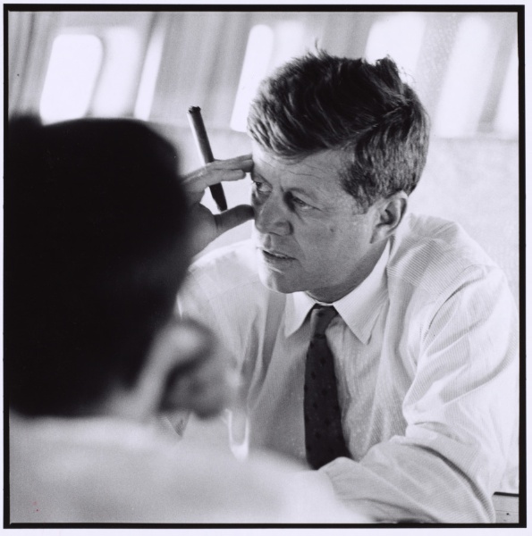 John F. Kennedy smoking cigar in his airplane The Caroline over West Virginia