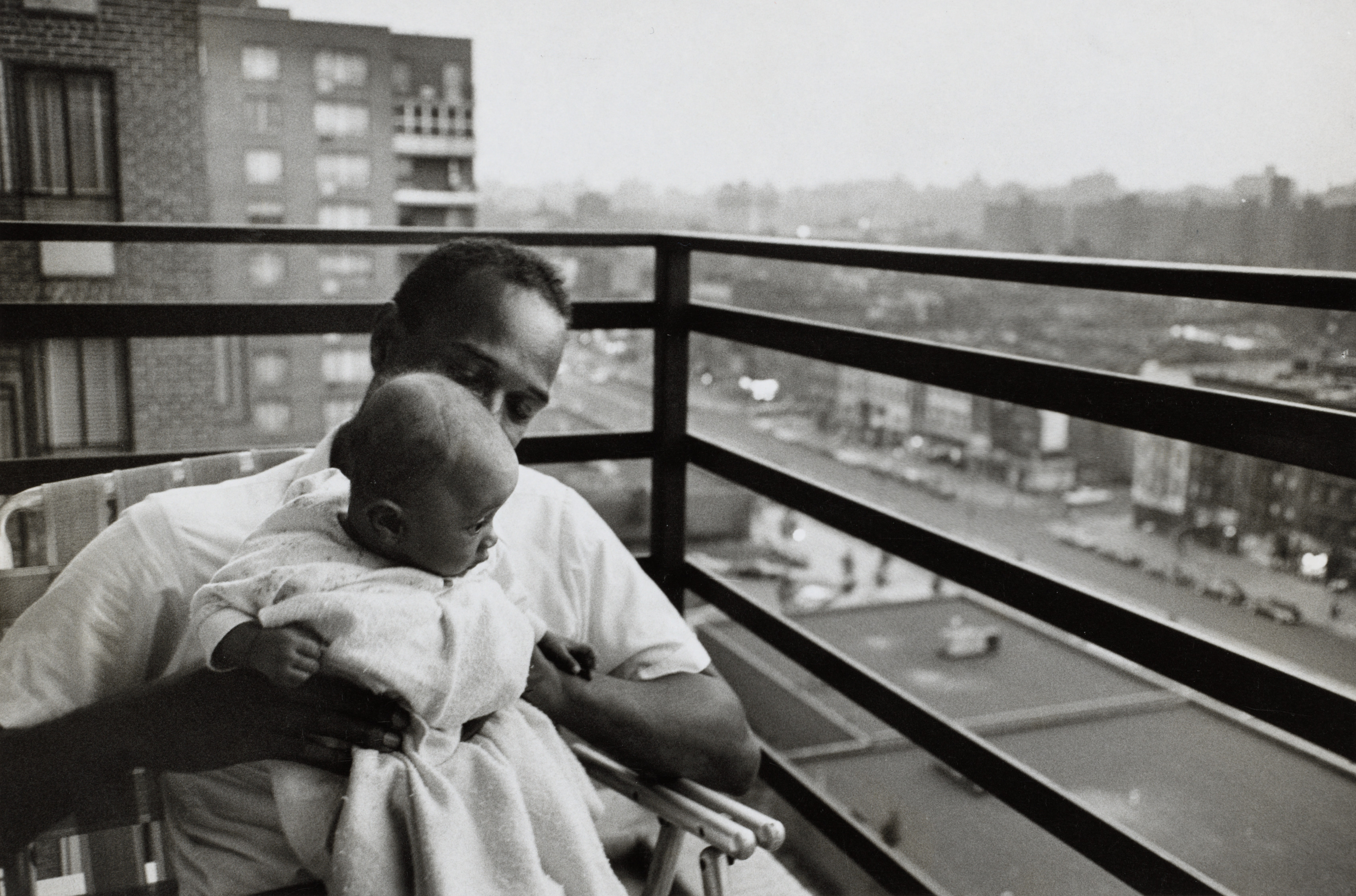 Sociology student with his 3 month old daughter on the balcony of his apartment, Harlem, New York City, USA